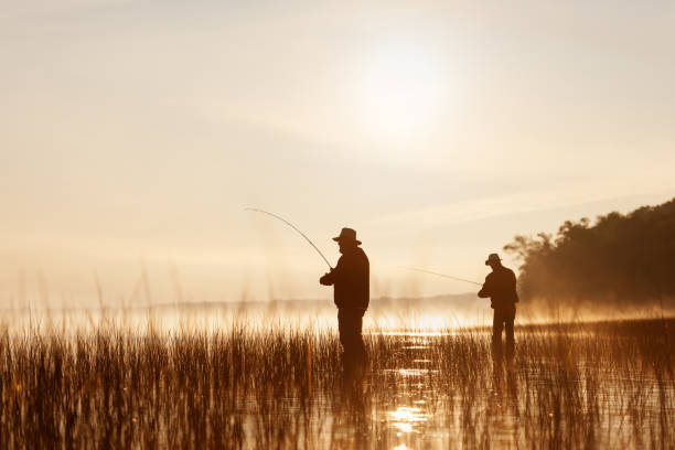 Two senior anglers fishing a misty Australian lake at dawn
